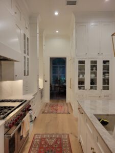 A kitchen with white cabinets and wood floors.