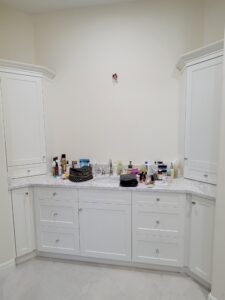 A bathroom with white cabinets and a large counter.