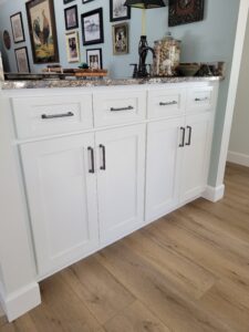 A white cabinet with black handles and knobs.