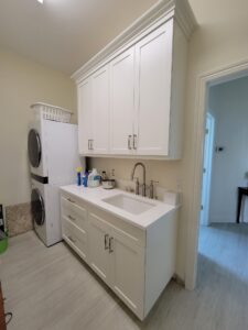 A kitchen with white cabinets and a washer dryer.