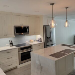 A kitchen with white cabinets and marble counter tops.