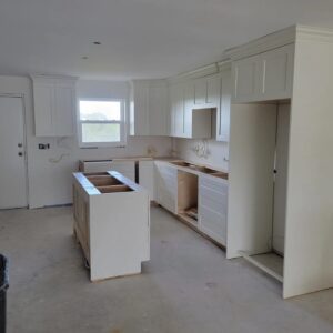 A kitchen with white cabinets and walls in the process of being remodeled.