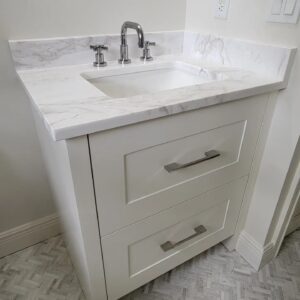 A white bathroom vanity with marble counter top.