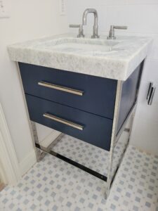 A bathroom with blue cabinets and white counter tops.