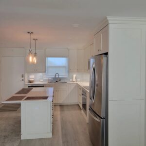 A kitchen with white cabinets and wood floors.