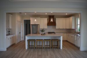 A kitchen with white cabinets and wood floors.