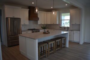 A kitchen with white cabinets and wooden floors.