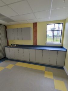 A room with yellow walls and grey cabinets.