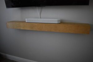 A white and black striped speaker on top of a wooden shelf.