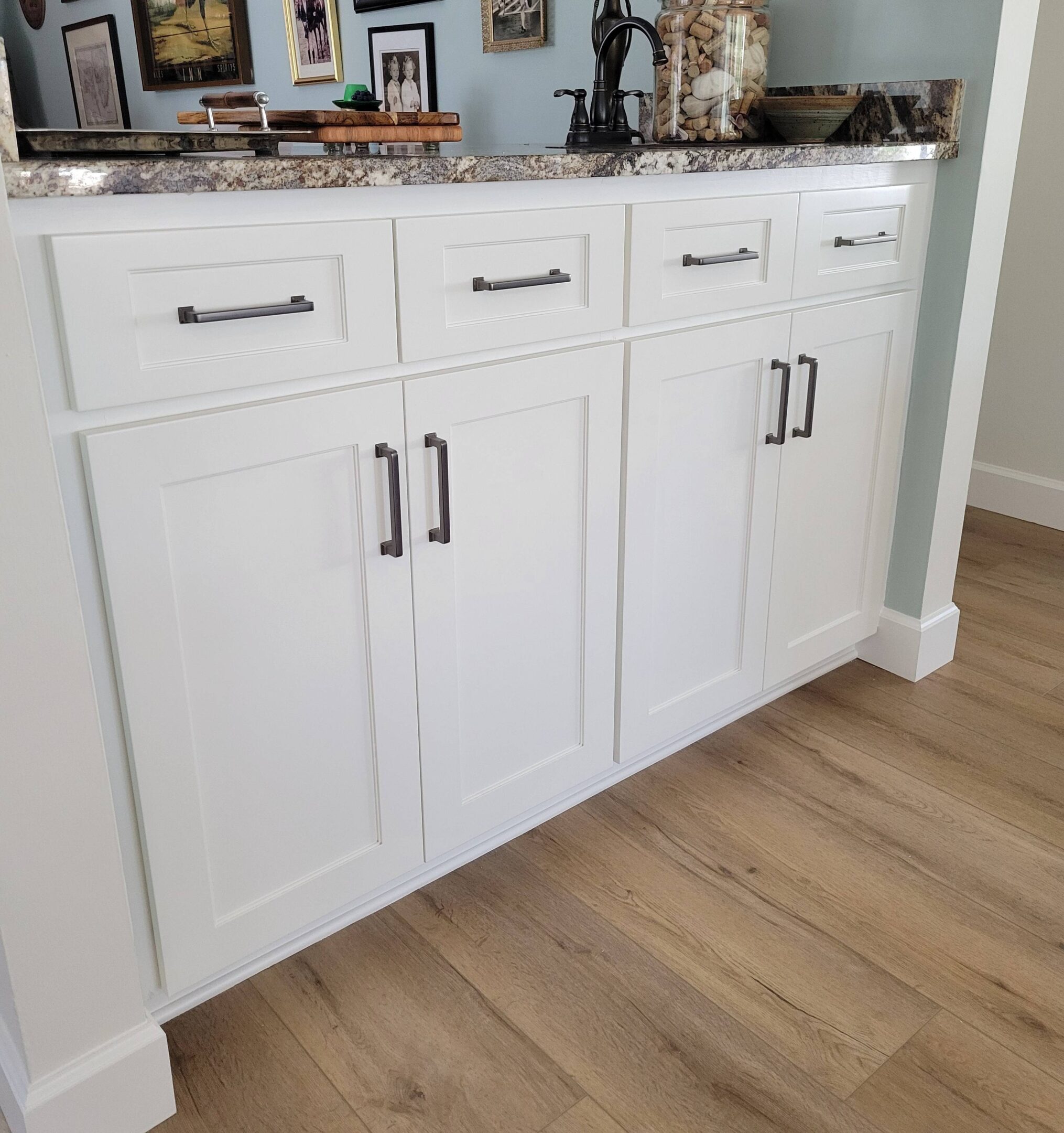 New Project (66) A white cabinet with black handles and a marble counter top.